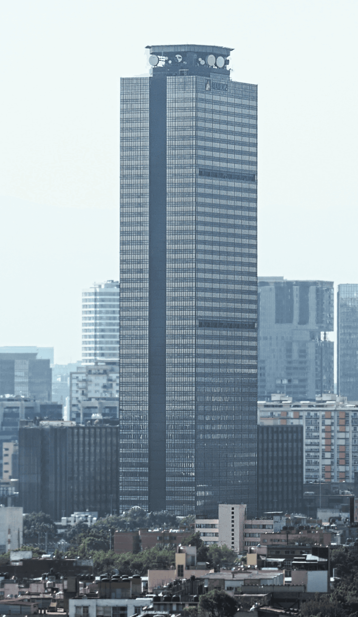 Edificio corporativo de gran altura con fachada de vidrio y estructura metálica en skyline urbano.