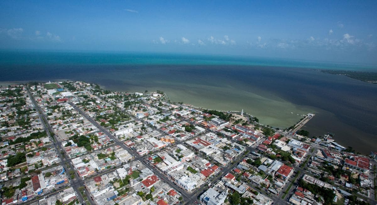 Vista aérea de la ciudad de Chetumal mostrando su desarrollo urbano, infraestructura vial en cuadrículas y su ubicación costera.
