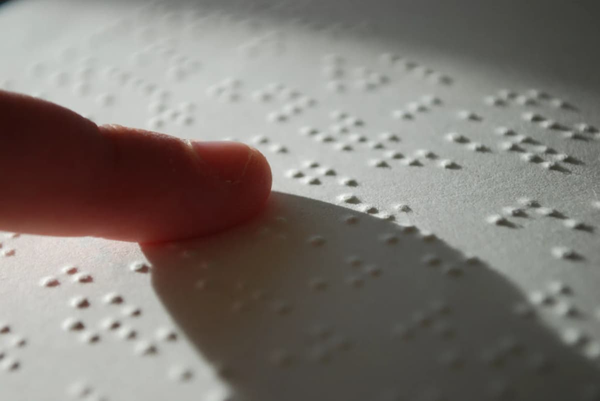 Un dedo lee texto en sistema Braille sobre una hoja