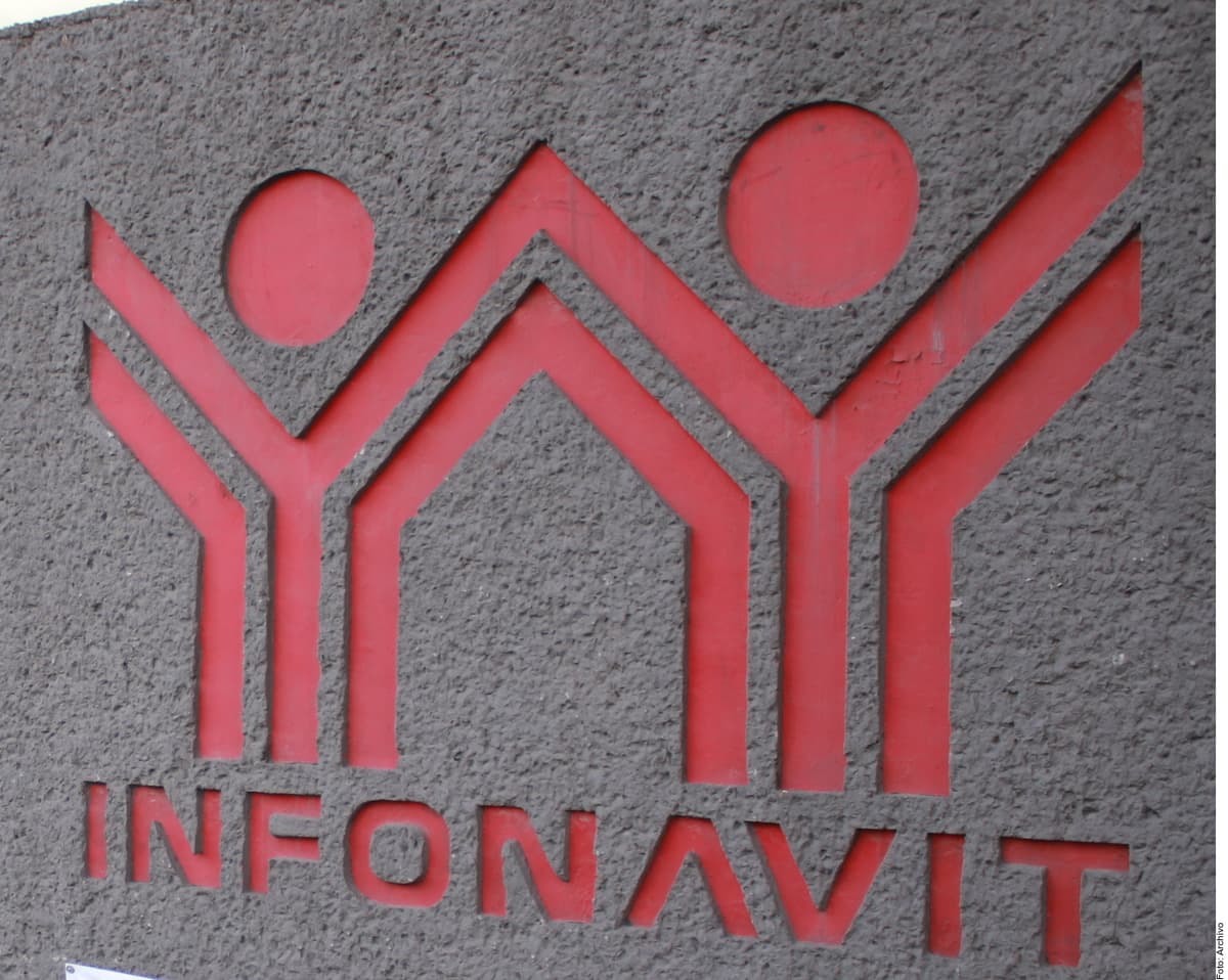 Logo del Infonavit en relieve rojo sobre pared gris de concreto.